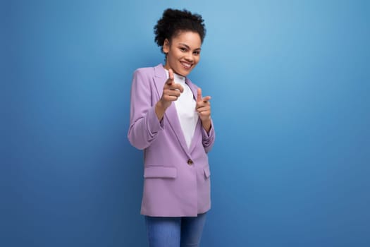 young positive successful latin business woman with tousled hairdo dressed in a jacket points her finger at having an idea.