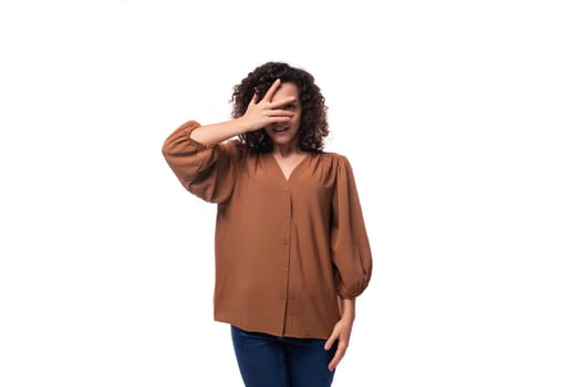 portrait of a young european curly woman with curled hair on a curling iron in a brown blouse isolated on a white background.