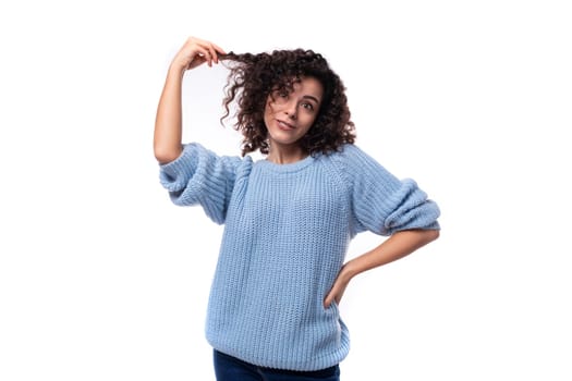 portrait of a young caucasian woman with curly natural dark hair dressed in a casual warm blue jacket.