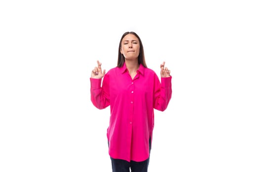 young brunette businesswoman dressed in a pink shirt crossed her fingers.