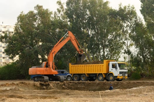 an excavator digs a hole under the foundation of a house and loads the earth into a dump truck 2