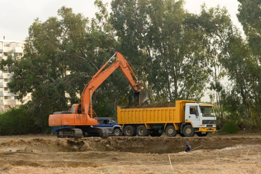 an excavator digs a hole under the foundation of a house and loads the earth into a dump truck 1