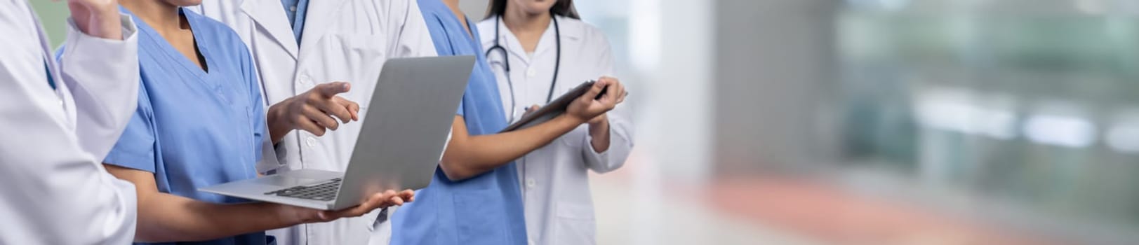 Medical staff team with doctor nurse and specialist working together with laptop and tablet on blur hospital corridor background. Medical and healthcare community in panoramic banner. Neoteric