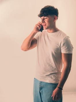 A man in a white shirt talking on a cell phone. Handsome Young Man in a White Shirt Engaged in a Phone Conversation