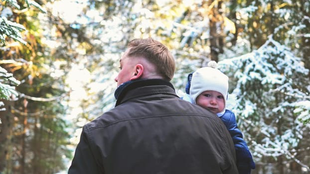 A father and his young son are walking through a winter forest