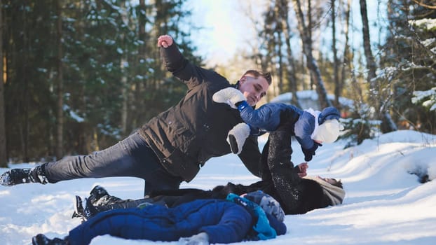 A mother and her child playing in the winter woods, falling in the snow with him