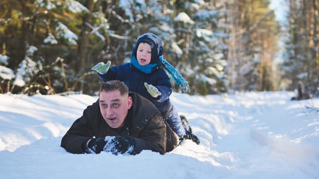 A father and his young son playing in the winter woods
