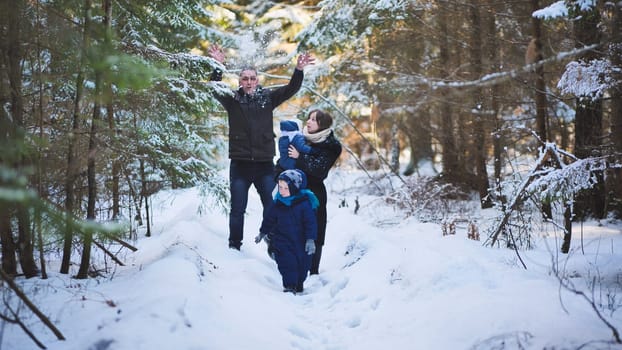 A young family is walking through a winter forest