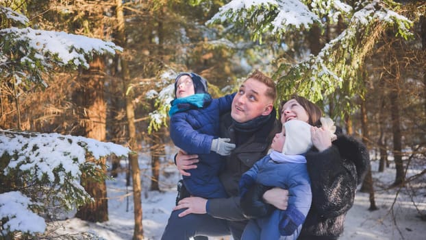 A happy family looks at the trees in the winter woods