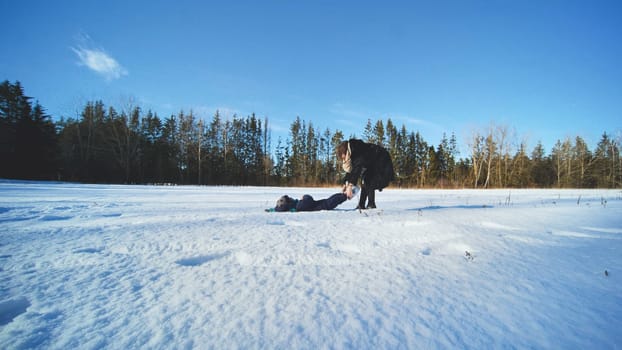 A mother drags her son through the snow while playing