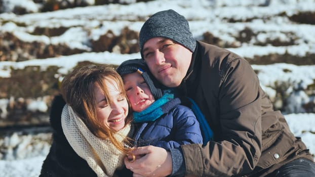 Parents embrace their son in the sunny winter weather