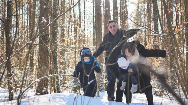 A young family wades through the branches in the winter woods