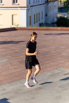 A young woman in black clothes running on stairs at city street early morning.