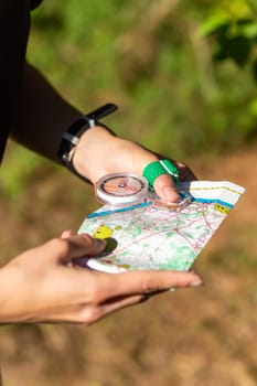 Woman holding a map and the compass during orienteering competitions. Athlete uses navigation equipment for orienteering,compass and topographic map.