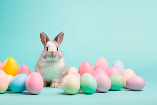 Cute Easter bunny sitting on the background of Easter eggs.