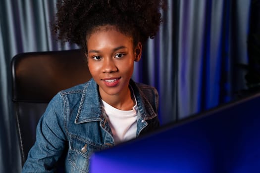 Young African American woman with surprise face, wearing blue jeans shirt and looking at final project document on laptop for planing next sequence. Concept of work at neat home place. Tastemaker.