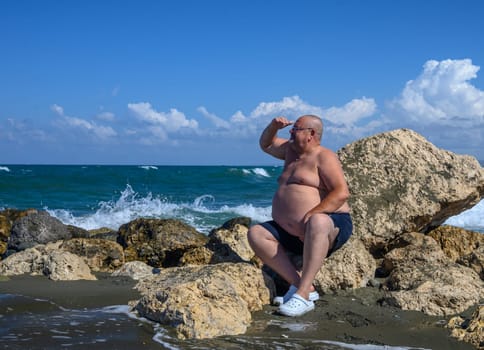 a man looks into the distance sitting on the stones