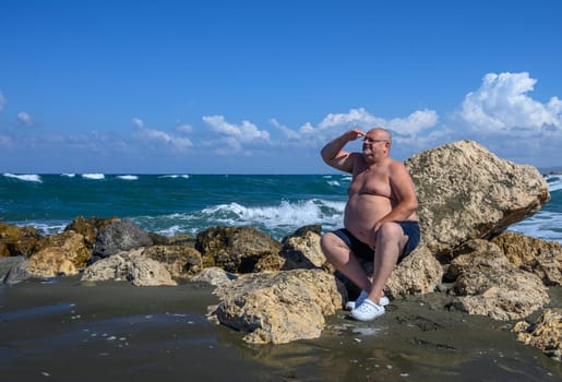 a man looks into the distance sitting on the stones 1