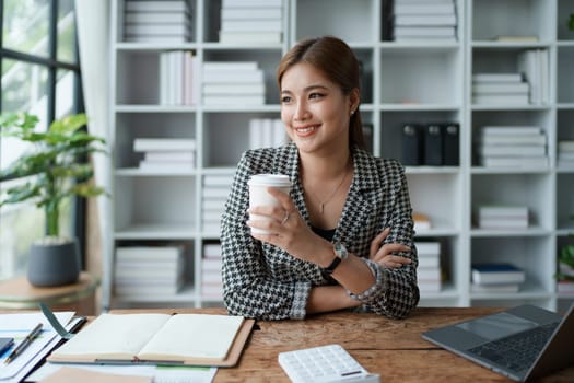 Portrait of a business woman talking on the computer and drinking coffee.