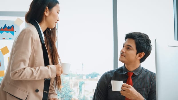 Two business people talk project strategy at office meeting room. Businessman discuss project planning with colleague at modern workplace while having conversation and advice on financial report. Jivy