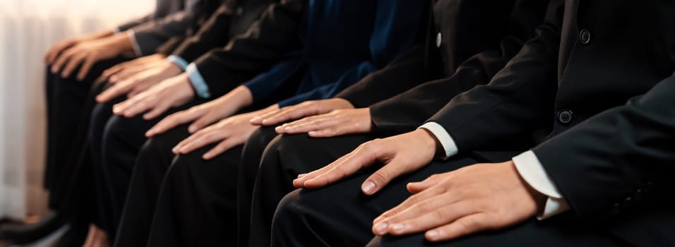 Asian job applicant waiting in line with good manners hand gesture and identical black formal wear for job interview. Modern and professional job seeker concept. Trailblazing