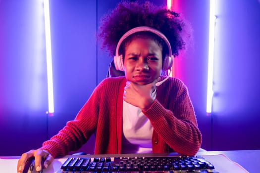 Gaming streamer, African girl playing online fighting with Esport skilled team wearing headphones in neon color lighting room. Talking other players planing strategies to win competitors. Tastemaker.