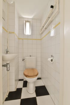 a small bathroom with black and white tiles on the floor, including a wooden seat in the toilet is next to the sink