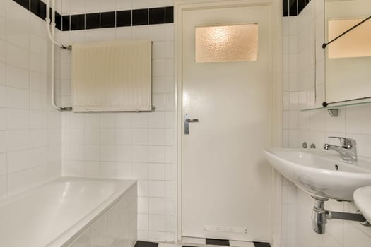 a bathroom with black and white tiles on the walls, tub, sink, and mirror in it's corner