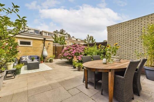 a patio area with furniture and flowers on the table, in front of a brick wall that has been painted white