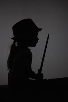 Silhouette of a child playing toy billiards.