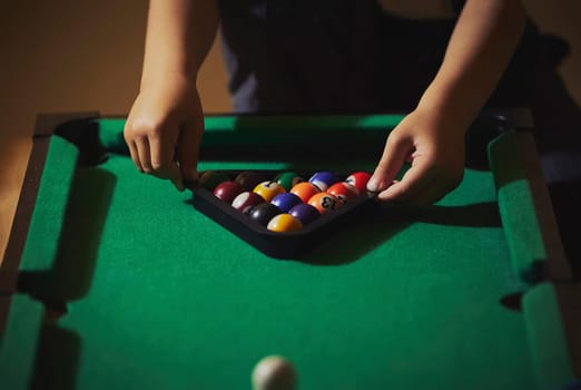 Charming child in retro clothes playing toy billiards.