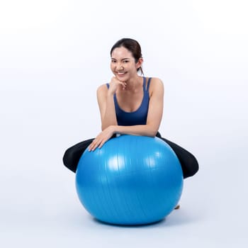 Young attractive asian woman portrait in sportswear with fit ball targeting on abs muscle for effective energetic daily workout routine. Studio shot and isolated background. Vigorous