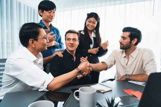 Diverse group of office employee worker shake hand after making agreement on strategic business marketing meeting. Teamwork and positive attitude create productive and supportive workplace. Prudent