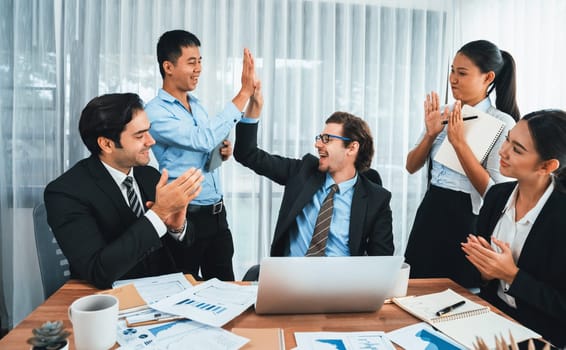 Group of happy businesspeople in high five gesture and successful efficient teamwork. Diverse race office worker celebrate after made progress on marketing planning in corporate office. Habiliment