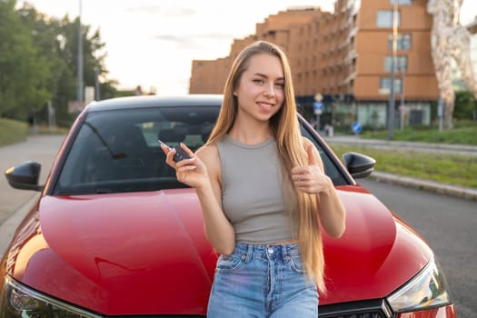 Young female customer buys a new red car and raises the key.