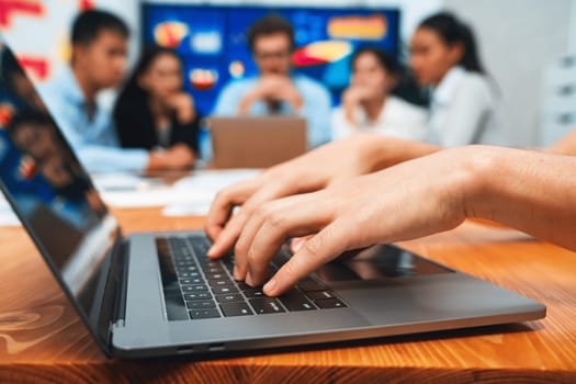 Closeup hand typing keyboard laptop with blurred background of business people using laptop to analyze financial data or data analysis display on screen background. Meticulous