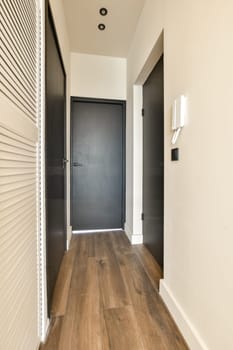 an empty hallway with wood flooring and black shutters on the door to the left side of the room