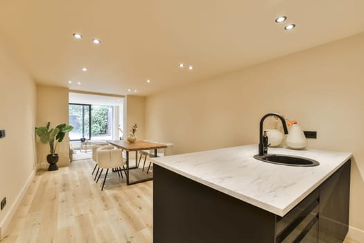 a kitchen and dining area in a house with white walls, hardwood flooring and marble counter tops on the island