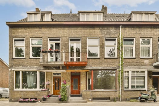 a house with many windows and plants in the front yard, on a clear blue sky overcasted day