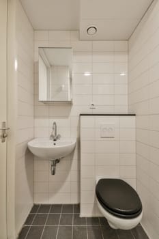 a small bathroom with black and white tiles on the floor, sink and toilet in the wall is made of glass