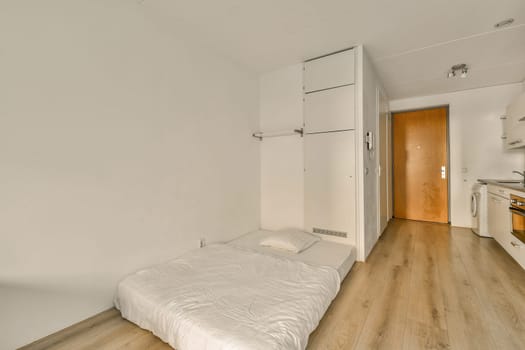 a bedroom with white walls and wood flooring on the wall, there is an empty bed in the room