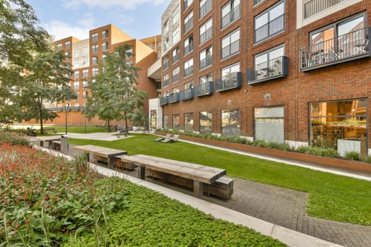 an urban park with benches and plants in the foreground area, surrounded by red brick buildings on either sides