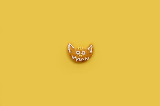 Funny glazed gingerbread cat lies on a yellow background. High quality photo