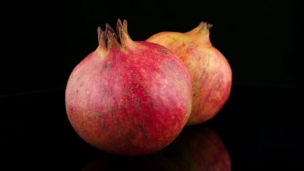 Ripe pomegranate fruit with leaves on black background