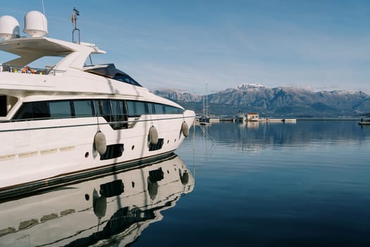 White double-deck yacht is moored at the pier against the backdrop of the mountains. High quality photo