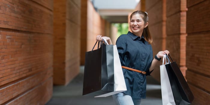 Young asian woman in shopping. Fashion woman in black with shopping bag walking around the city after shopping. Black friday.