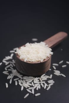Raw white rice on a wooden spoon .