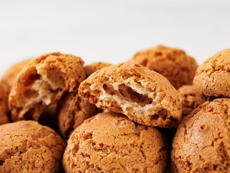 pile of cookie amaretti on white marble background - traditional Italian Sardinian pastry. Amaretti biscuit cookies made from almond or apricot kernels with copy space