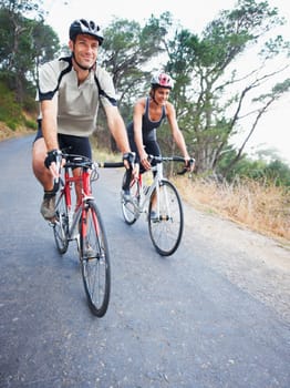 Happy couple, cycling and road in nature for, fitness, training or travel on bicycle together. Outdoor, people and exercise on bike for fun, workout and path in countryside for adventure or journey.