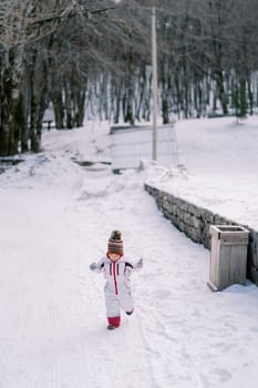 Small child walks along a snowy road in the park, balancing with his hands. High quality illustration